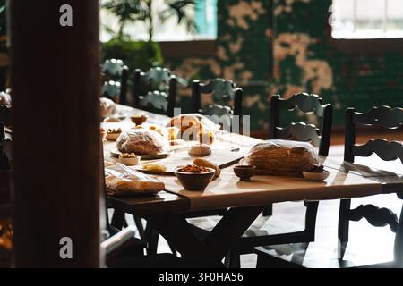 Rustic long dining table set with bread and snacks in organic cafe Stock Photo