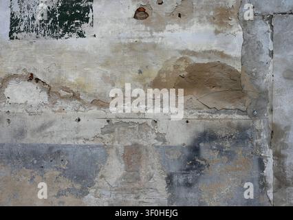 Horizontal close up of a weather beaten multicolor deteriorating wall surface with scratched cement layers Stock Photo