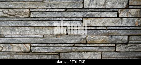 Horizontal close up of machine sawn flat unpolished granite stone with recessed mortar, showing layered light gray and white granite Stock Photo