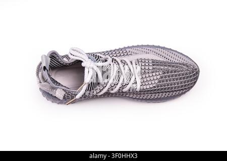 Gray sneaker close-up featuring textured knit upper, light gray laces, translucent sole, modern sporty design, clean minimalist background, bright eve Stock Photo