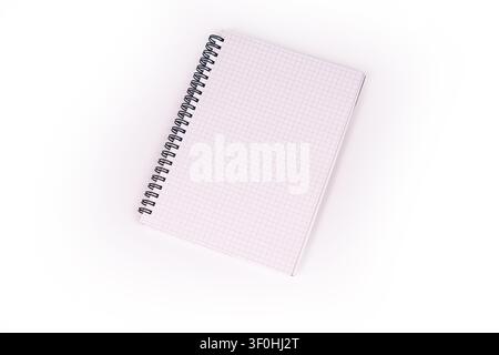 Spiral notebook with pink grid pages diagonally placed, providing a subtle texture, soft lighting, stark white background, minimalistic composition, a Stock Photo