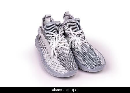 Modern athletic sneakers on white background, featuring gray and white knit upper, translucent soles, textured pattern, bright even lighting, minimali Stock Photo