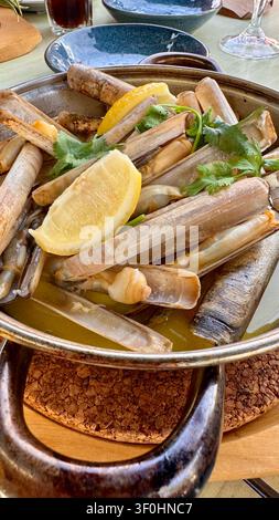 Seafood dish with clams, lemon, and herbs served on a table in a restaurant setting during daytime Stock Photo