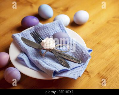 Naturally colored stylish Easter eggs in a plate, decorative flowers, on a wooden table Stock Photo
