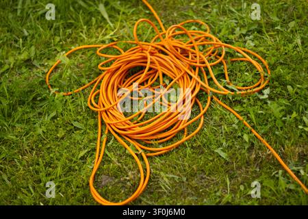 Orange extension cord on green grass Stock Photo
