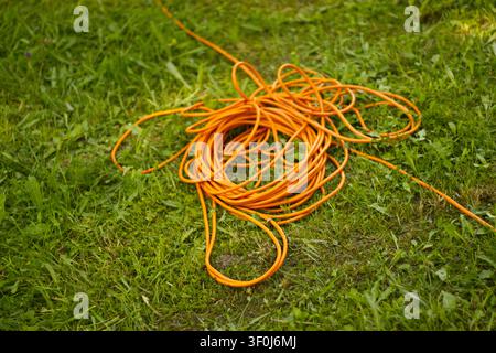 Orange extension cord on green grass Stock Photo