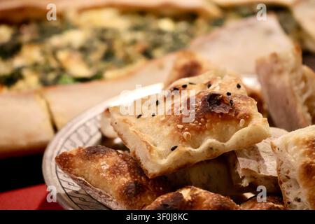 Freshly baked Turkish pide bread pieces with sesame and nigella seeds served in a bowl, Anatolian restaurant meal Stock Photo