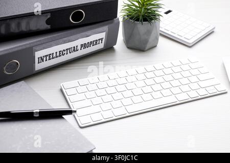 Intellectual property. Folders, computer keyboard, notebook and pen on white wooden table Stock Photo