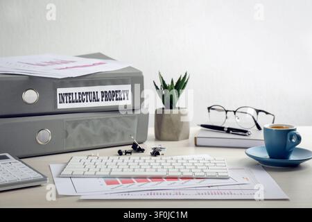 Intellectual property. Folders, computer keyboard and notebook on wooden table Stock Photo