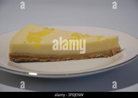 Close-up of a classic cheesecake slice on a white background Stock Photo