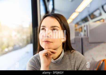 Thoughtful woman looking through window while traveling by train Stock Photo