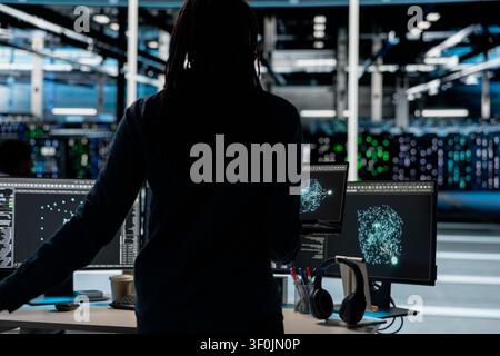 Data center engineer uses a laptop computer in a data center to support automation monitoring and reliable server workflows. Stock Photo