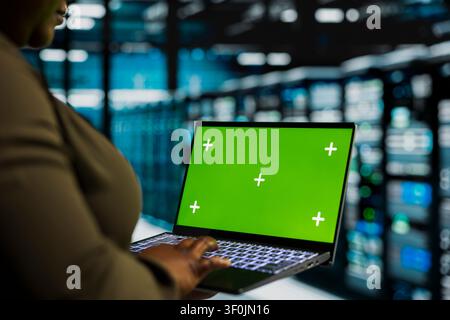 Data center administrator works with a chroma key laptop, using an editable screen to install and configure equipment. Stock Photo