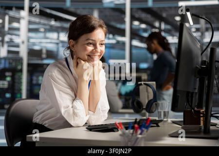 Cheerful data center engineer celebrates improved system results in a data center after improved performance and completed server operations. Stock Photo