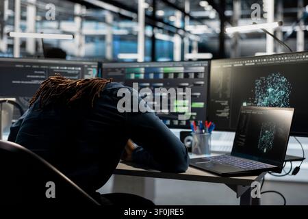 Exhausted data center engineer falls asleep while reviewing data analysis graph to reduce equipment failure. Stock Photo
