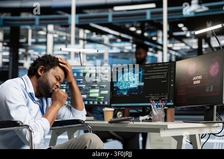 Worker using a wheelchair in a data center uses a computer to install and configure equipment, supporting reliable infrastructure operations. Stock Photo