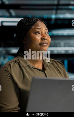IT administrator working with notebook computer to do maintenance in server facility with setup helping companies stay connected. Stock Photo