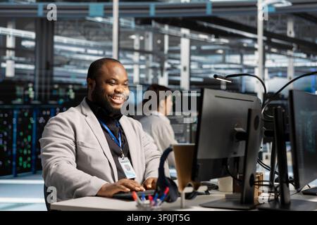 Smiling IT specialist uses a clipboard to review server infrastructure, diagnostics and AI technology in a data center. Stock Photo