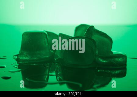 Pure clean transparent Ice Cubes Melting On Mirror Surface In Neon Green Light Still Life cosmetic spa Stock Photo