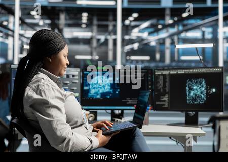 Smiling data center staff member reviews data analysis graph to reduce infrastructure failure. Stock Photo