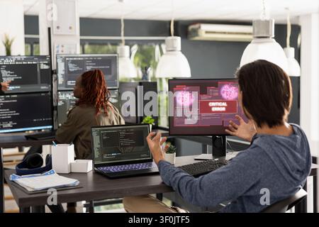 Stressed male developer reacts with shock to critical system error on his computer. Young adult programmer shows concern after discovering major bug or potential cybersecurity threat. Stock Photo