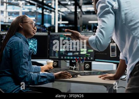 Data center collaborating engineers doing planning solutions, reviewing data analysis graph to reduce failures. Stock Photo