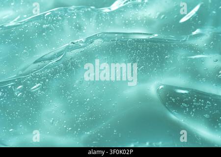 A captivating macro photograph showing the texture of teal gel, highlighted by numerous bubbles suspended within. The smooth surface reflects light be Stock Photo