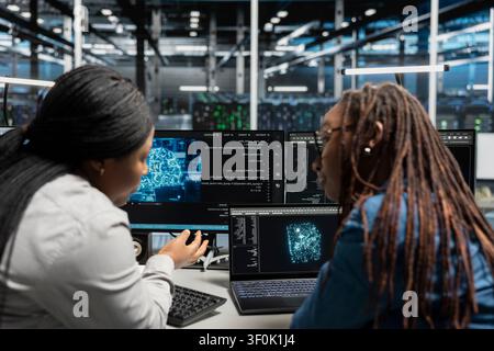 Engineers collaborating, inspecting neural network server room used for machine learning. Stock Photo