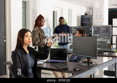 Female programmer works with 3d interface in office, testing code for web development. Innovative developer raises arms to interact with holographic screen while analyzing frontend data. Stock Photo