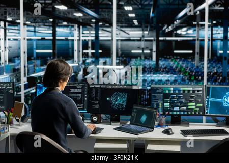 Server room computer scientist running simulations for AI driven prediction, tracking performance. Stock Photo