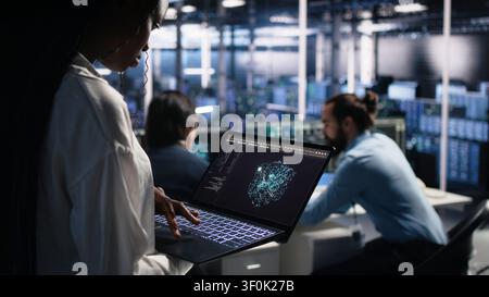 Data center technician reviews AI systems and neural network parameters on a tablet inside a data center. Stock Photo