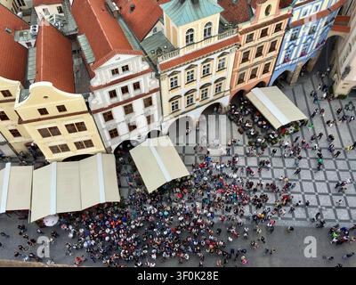 Crowds gather among colourful baroque buildings and striped awnings in Prague's historic Old Town Square. Stock Photo