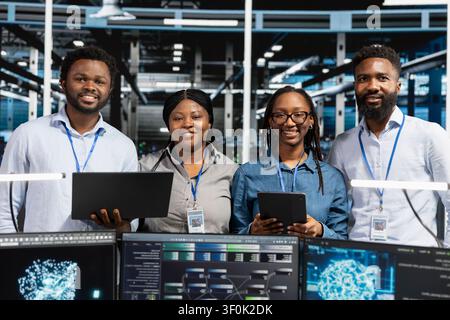 Happy data center team reviews data analysis graph to reduce equipment failure. Stock Photo