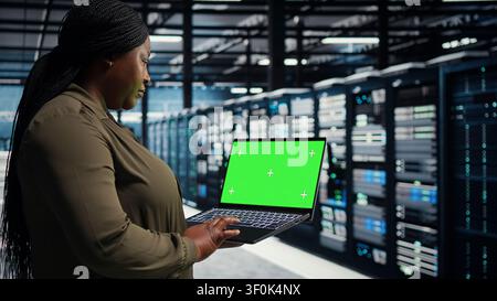 Programmer uses an isolated screen laptop in a server room for editable AI infrastructure review. Stock Photo