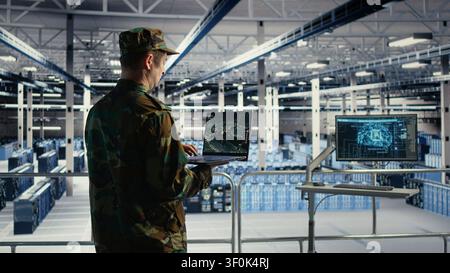 Military engineer in a military data center monitors satellite coordinates with radar software, scanning aerial activity for defense operations. Stock Photo