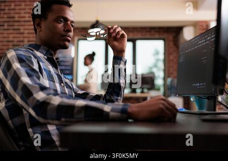 Pensive network engineer reflecting at failed data processing operation documents data protection, software systems and secure infrastructure in a technology workspace. Stock Photo