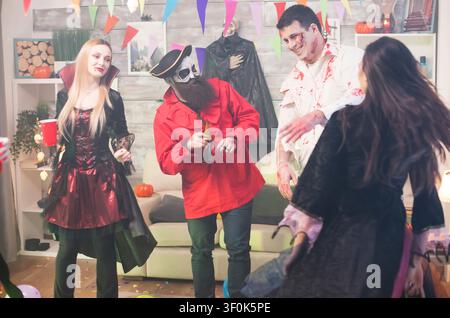 Man dressed up like scary zombie with blood on his face connects costume makeup, spooky characters and festive Halloween fun in a themed celebration setting. Stock Photo