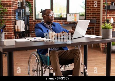 Disabled businessman uses a laptop in an office to plan project strategy, research management ideas and work on a startup company task. Stock Photo