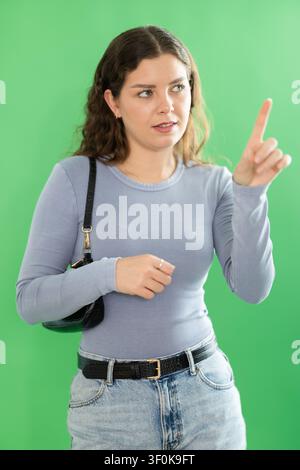 Young woman using virtual screen in front of green screen Stock Photo