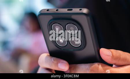 This image features a close up of a human hand holding a mobile device with a multiple camera lens system prominently displayed, set against a softly Stock Photo