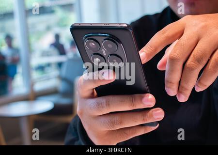 The image features a close up view of a person hands holding a mobile device in a modern indoor environment illuminated by natural light creating a so Stock Photo