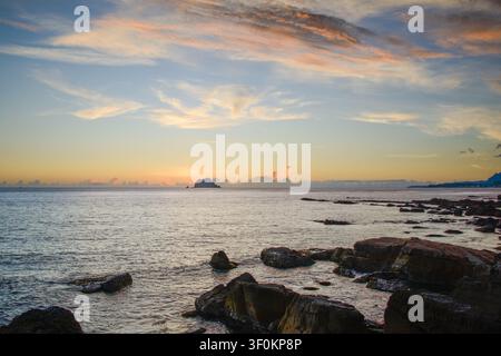 A serene sunrise view of Keelung Islet seen from the rocky coastline of Wanli, New Taipei City, Taiwan, during the early morning hours. Stock Photo