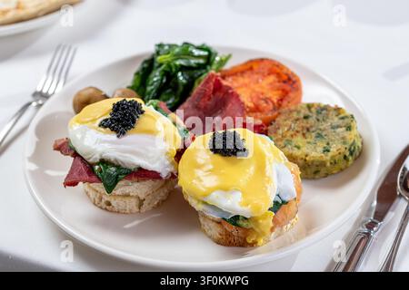 Eggs benedict with salmon, spinach, hollandaise and black caviar topping Stock Photo