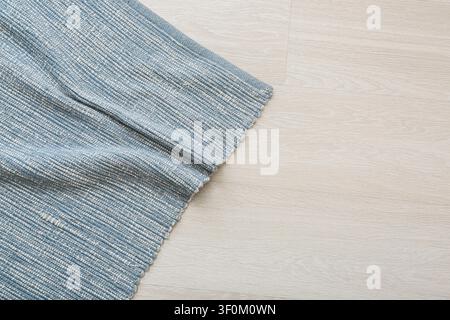 Blue and white woven fabric rug on light wooden floor with copy space, home decor and interior design Stock Photo