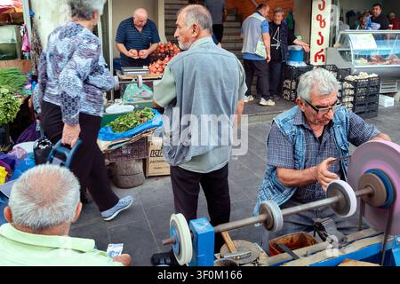 A knife sharpener craftsman at the bustling Dezerter Bazaar Market, Tbilisi, Georgia, Caucasus, Eurasia, Eastern Europe Stock Photo