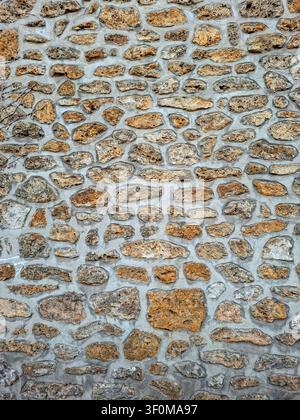 This rustic wall features a beautiful natural sandstone texture with various colors. The unique design adds character to the surrounding area during d Stock Photo