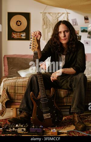 Portrait of Long Haired Man Holding Electric Guitar at Home Studio Stock Photo
