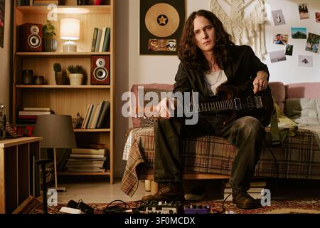 Portrait of Young Man Holding Electric Guitar in Home Studio Stock Photo