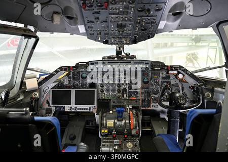 Close-up interior view of an airplane cockpit flight deck showing instrument panel, gauges, throttles and overhead switches, suitable for aviation. Stock Photo