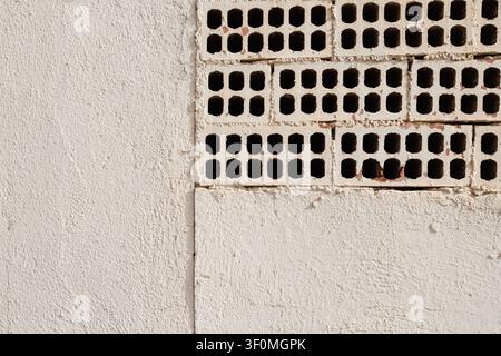 White Painted Wall with Exposed Perforated Bricks Stock Photo